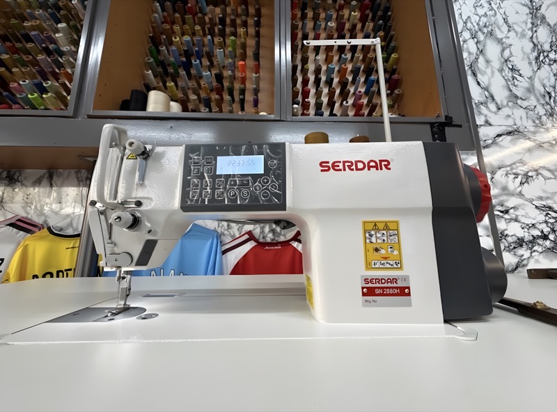 Computergesteuerte Industrienähmaschine von Serdar vor der Garnwand